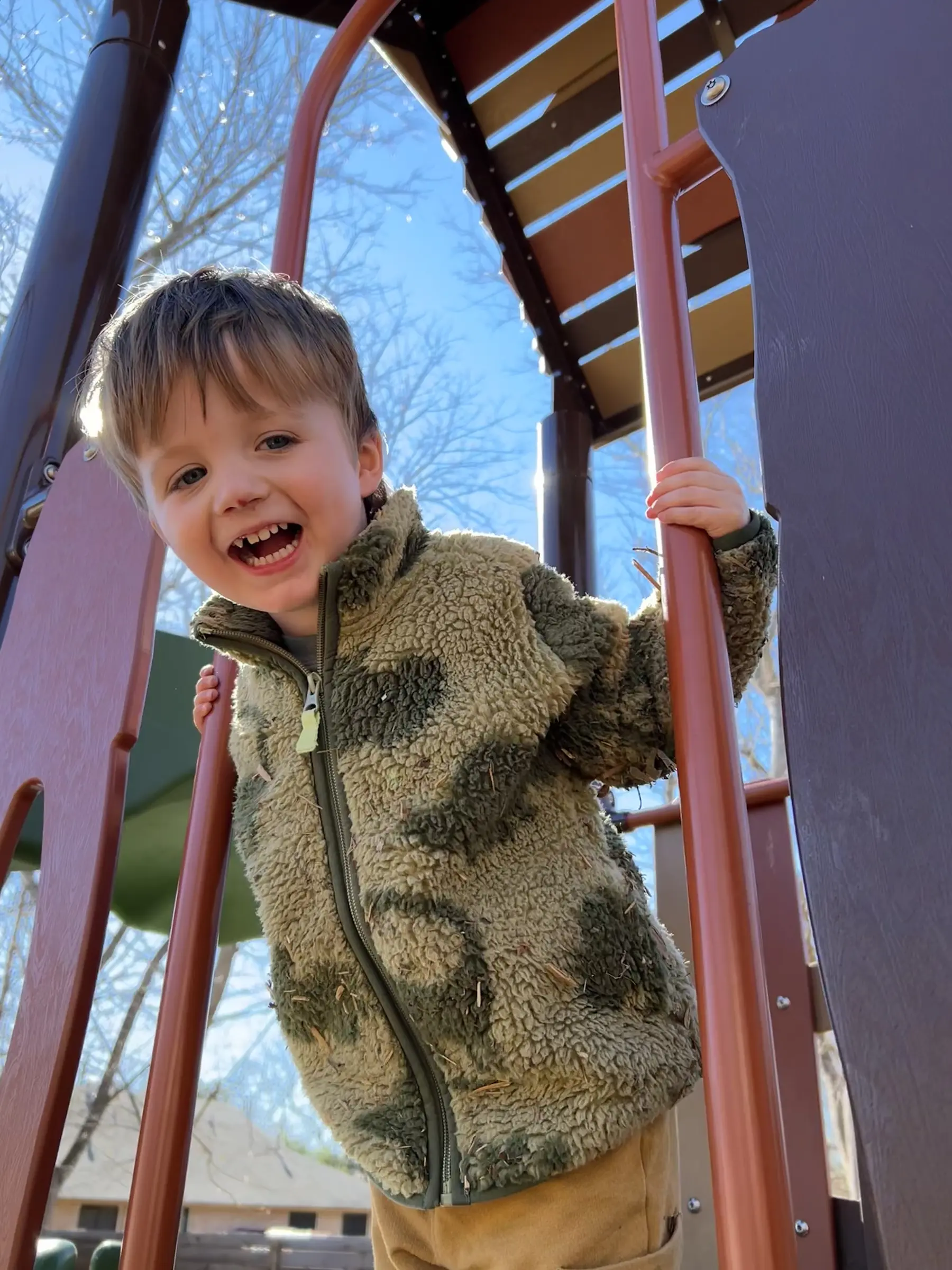 A Mockingbird child climbing outdoors beneath a bright blue sky