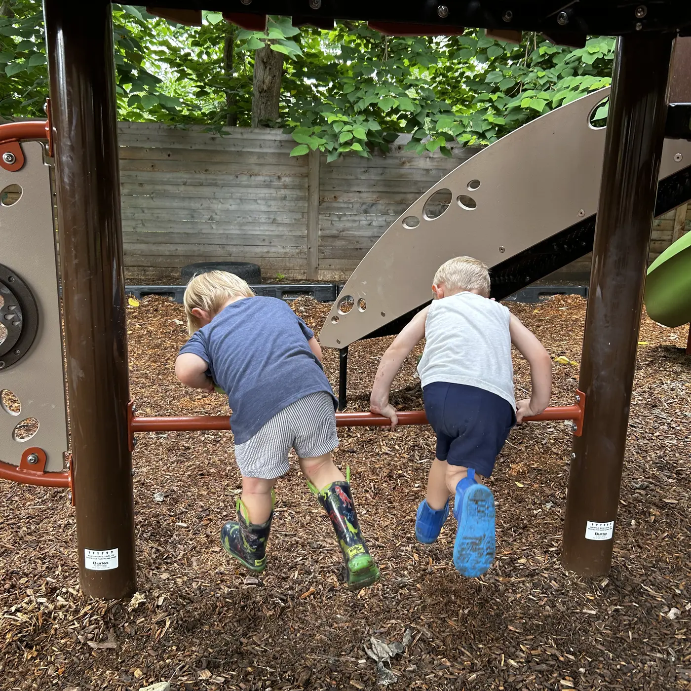 Two Mockingbird children climbing onto the playscape together