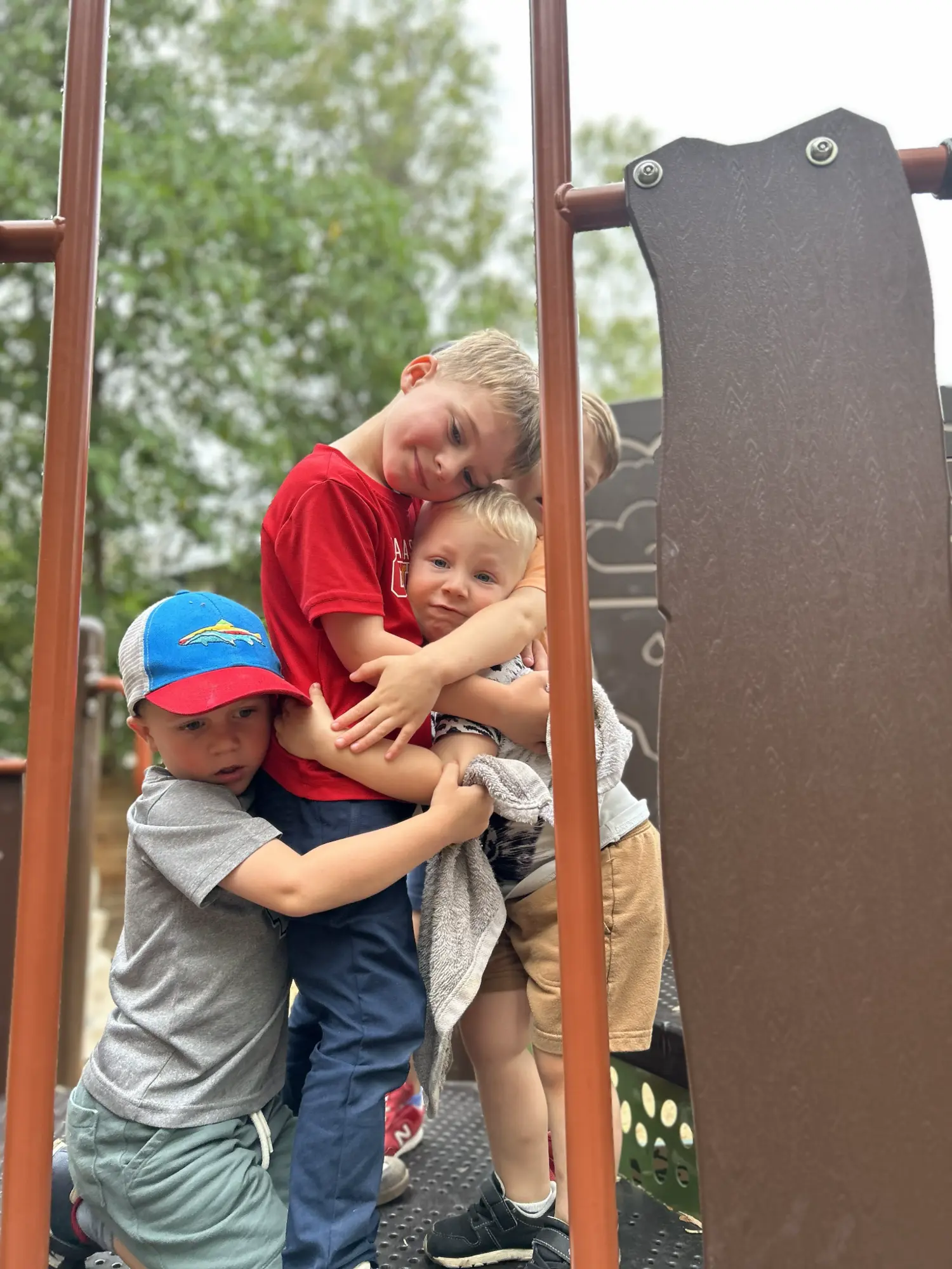 Mockingbird children embracing one another on the playscape