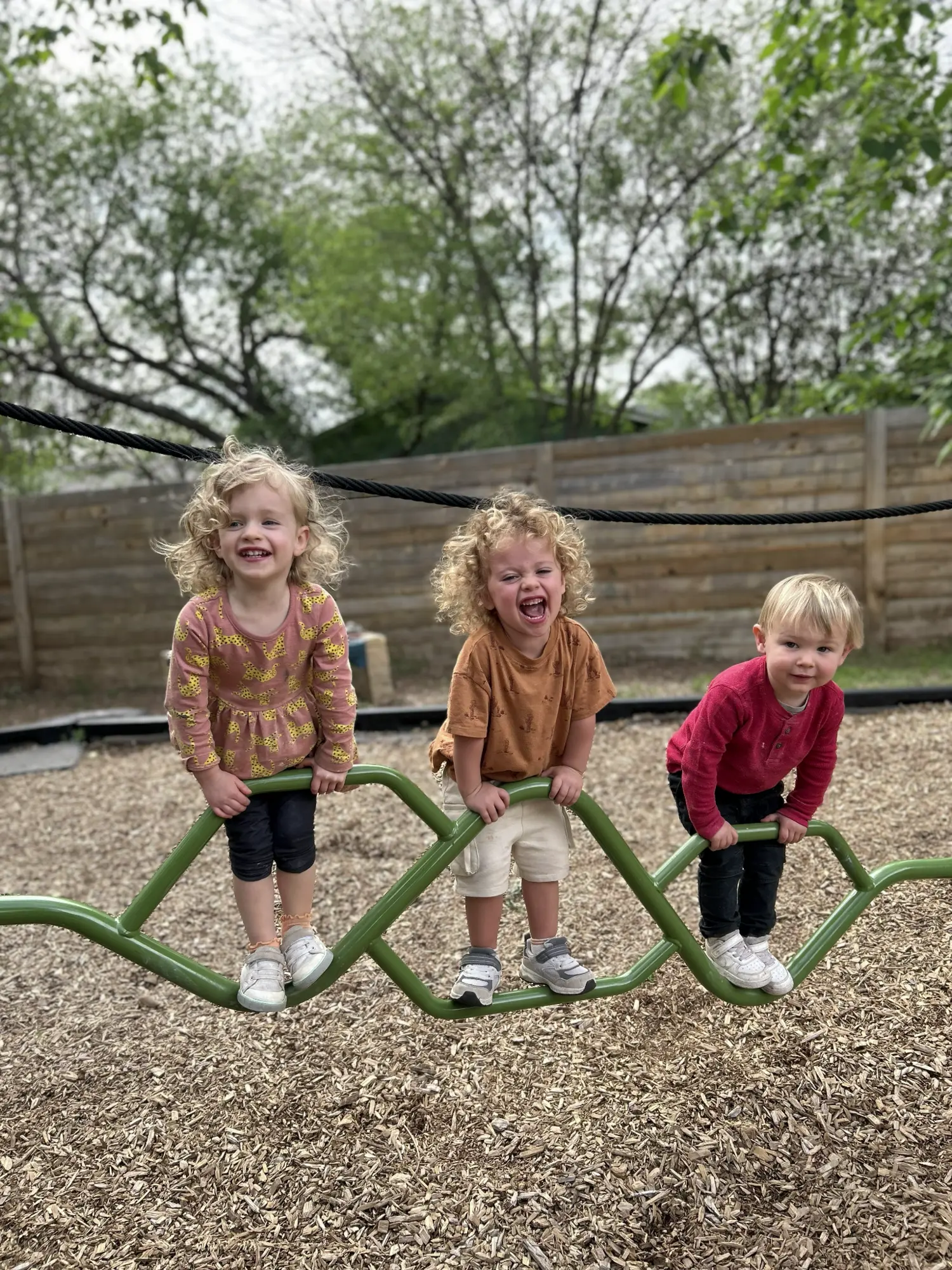 Three smiling Mockingbird children balancing together outdoors